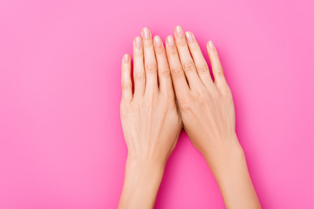 top view of female hands with pastel enamel on nails on pink backgroundの写真素材