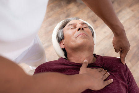 high angle view of african american masseur massaging middle aged man on massage tableの写真素材