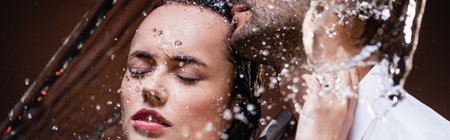 sensual woman with closed eyes near man under water splashes on dark background, bannerの写真素材
