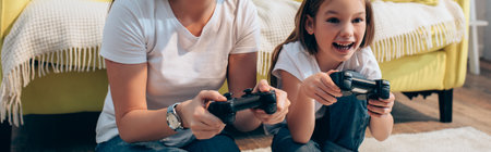Happy daughter playing with joystick near mother at home, banner