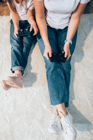 KYIV, UKRAINE - OCTOBER 19, 2020: Cropped view of mother and daughter playing with joysticks while sitting on floorの写真素材