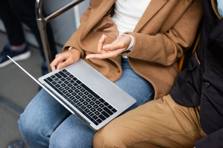 cropped view of african american woman pointing with finger at laptop near man in subwayの写真素材
