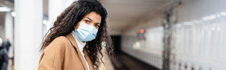 young african american woman in medical mask in subway, bannerの写真素材