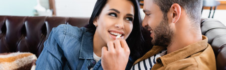 young man feeding cheerful girlfriend with popcorn, bannerの写真素材