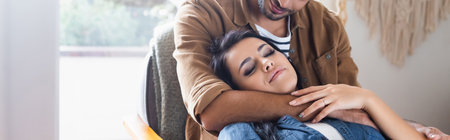 young man embracing happy girlfriend at home, banner