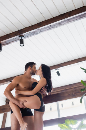 sexy shirtless man kissing passionate brunette woman in black lace pantiesの写真素材