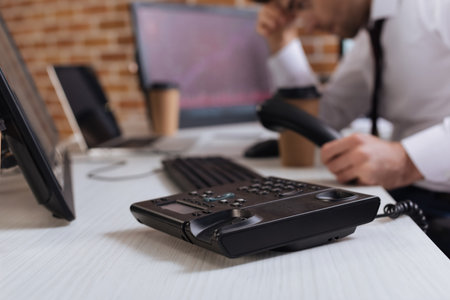 Cropped view of telephone on table near forex businessman and computers on blurred backgroundの写真素材