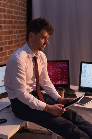 Forex businessman holding digital tablet near computers with charts on blurred background