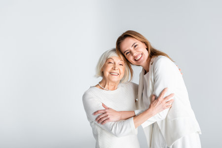 senior mother hugging with happy daughter isolated on grayの写真素材