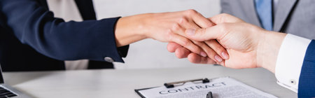 partial view of business partners shaking hands near contract, bannerの写真素材