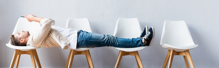 Man lying on chairs and using smartphone while waiting in hall, banner