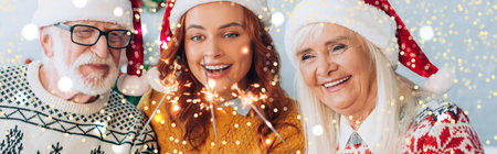 panoramic orientation of happy senior couple with daughter holding sparklers on christmas, bokeh...