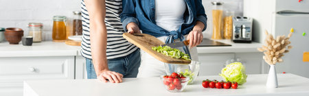 cropped view of couple preparing salad in kitchen, bannerの写真素材