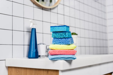 Colorful sponges on sink near detergent on blurred background in bathroomの写真素材