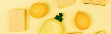 Top view of bottle of dishwashing liquid, fresh lemons and sponges on yellow background, bannerの写真素材