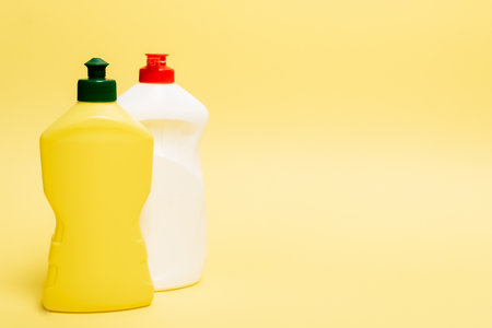 Bottles of dishwashing liquid on yellow background with copy spaceの写真素材