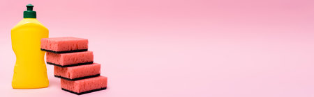 Bottle of dishwashing liquid and sponges on pink background, bannerの写真素材