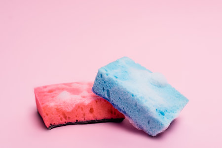Colorful sponges with soapsuds on pink backgroundの写真素材