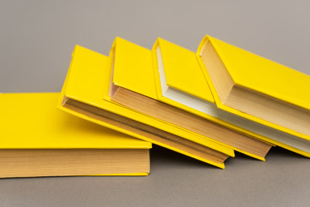 stacked yellow notebooks and books on grayの写真素材