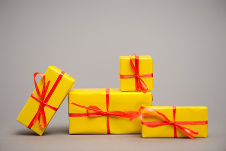 wrapped yellow presents with red ribbons on gray