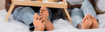 Cropped view of feet of african american couple on bed on blurred background, bannerの写真素材