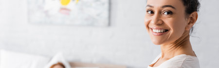 happy african american woman smiling at camera at home, bannerの写真素材