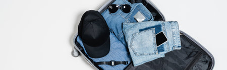 top view of mobile phone in pocket of jeans near denim shirt, black cap, electronic wristwatch and...