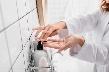 Cropped view of woman applying cosmetic cream in bathroomの写真素材