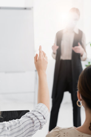 cropped view of woman raising hand near speaker on blurred background