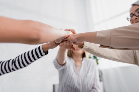 group of multiethnic women holding hands together during seminar