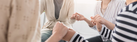 partial view of women holding hands during seminar, banner