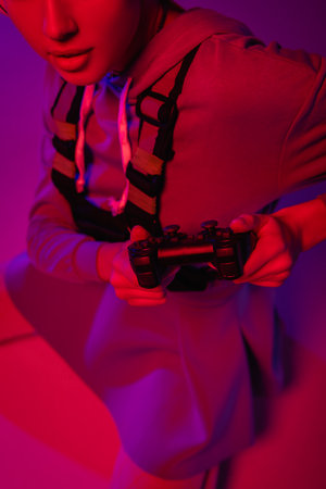 cropped view of young woman holding joystick on purple
