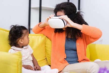 toddler african american kid looking at mother in vr headsetの写真素材