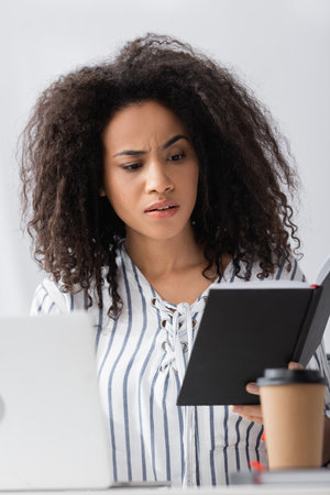 african american freelancer looking at notebook while working from home