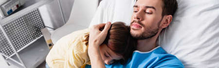 diseased father embracing daughter while lying in hospital, bannerの写真素材