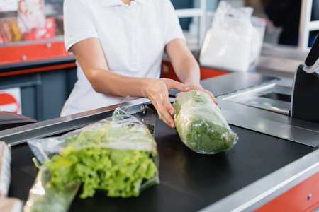Cropped view of cashier taking lettuce from supermarket checkoutの写真素材