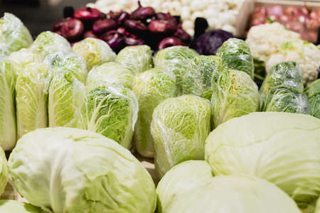 Close up view of fresh cabbages near vegetables on blurred background in supermarketの写真素材