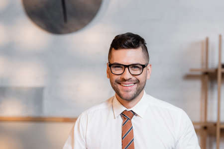 happy architect in eyeglasses smiling at camera in architectural agencyの写真素材