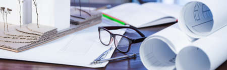 blueprints, architectural maquette, eyeglasses and divider on desk in office, banner