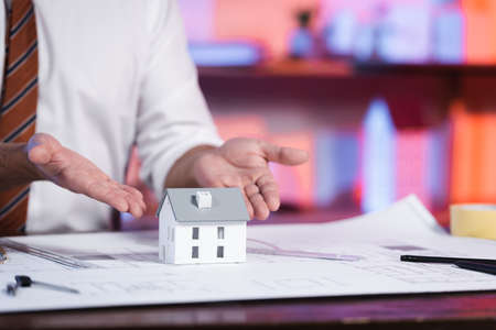 partial view of architect pointing with hands at house maquette, blurred background