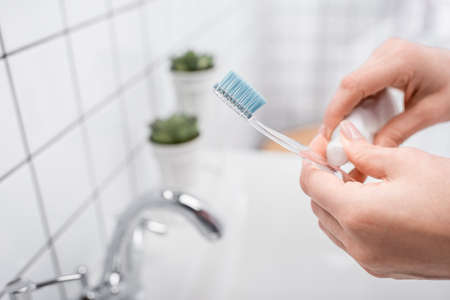 cropped view of woman holding toothbrush with toothpasteの写真素材