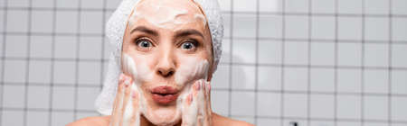 surprised woman applying foam cleanser in bathroom, banner