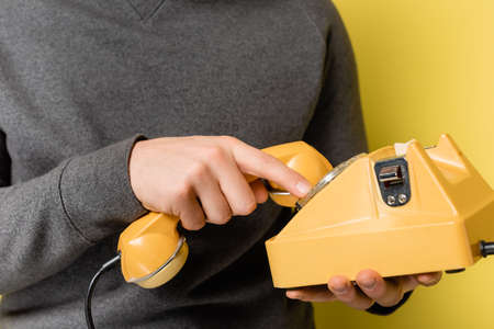 Cropped view of man using retro telephone on yellow backgroundの写真素材