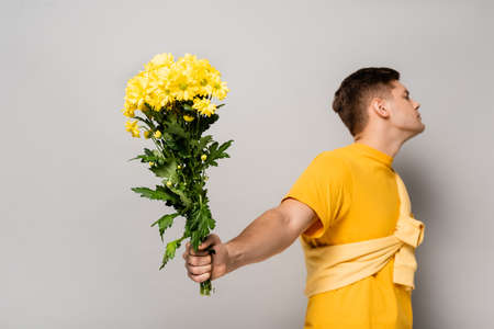 Yellow chrysanthemums in hand of man blurred on gray backgroundの写真素材