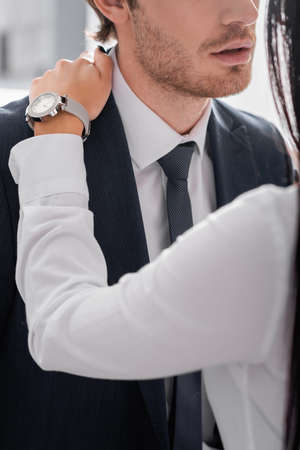 cropped view of businessman flirting with colleague and touching his shoulder in office, blurred foregroundの写真素材