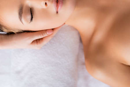 cropped view of masseur doing facial massage to young woman in spa salonの写真素材