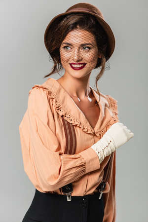 happy woman in hat and retro blouse looking away isolated on gray