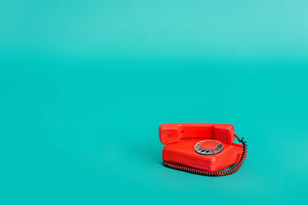 bright red vintage telephone on turquoise background with copy spaceの写真素材