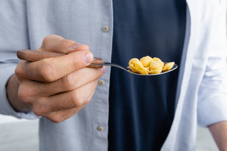 cropped view of man holding spoon with corn flakes