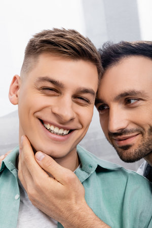 close up of homosexual man touching face of smiling husband at homeの写真素材